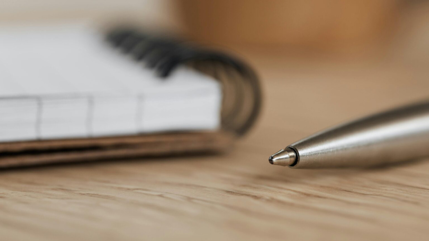Billedet viser en kuglepen og en notesblok