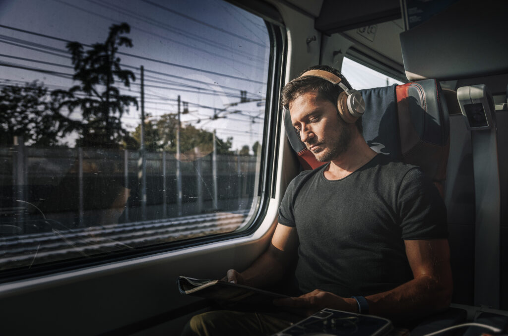 Ung mand rejser i toget med høretelefoner på